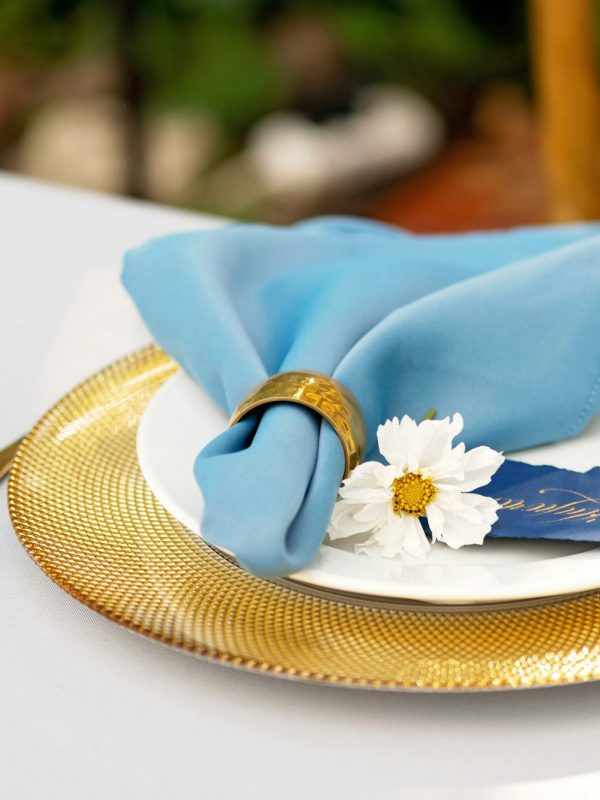 Elegant and chic wedding table setting in gold and blue colors and fresh flowers.